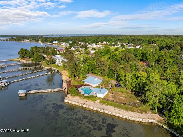 aerial overview of property's location with a large body of water, a heavily wooded area, and a pool area