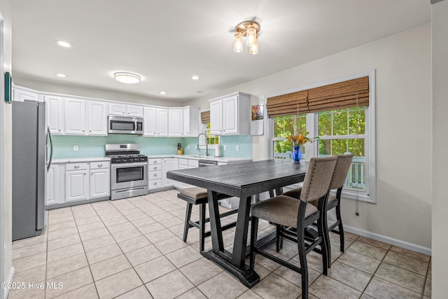 kitchen with stainless steel appliances, light tile patterned floors, light countertops, white cabinets, and recessed lighting