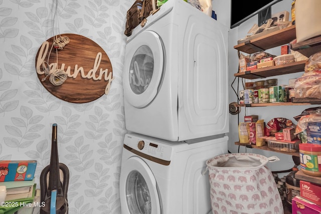 washroom featuring stacked washing maching and dryer, laundry area, and wallpapered walls