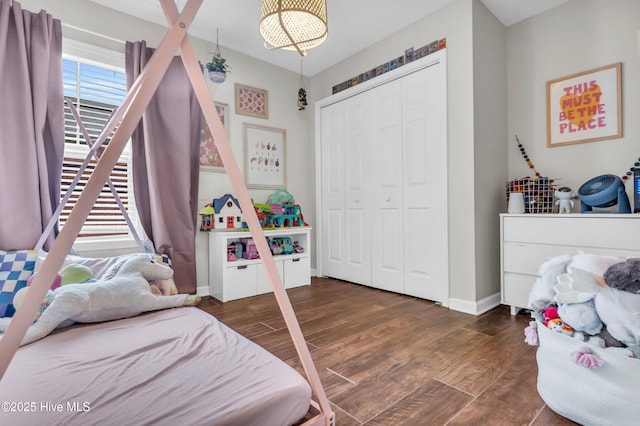 bedroom with baseboards, wood finished floors, and a closet