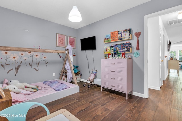 bedroom with baseboards, visible vents, and wood finished floors