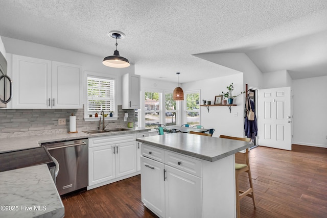 kitchen with a sink, dishwasher, a breakfast bar area, decorative backsplash, and a kitchen island