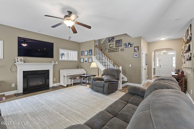 living area with stairway, arched walkways, plenty of natural light, and ceiling fan with notable chandelier
