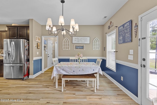 dining room featuring baseboards, a notable chandelier, light wood-style flooring, and visible vents