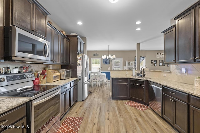kitchen with dark brown cabinetry, light wood-type flooring, a chandelier, a sink, and appliances with stainless steel finishes