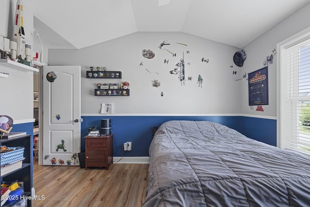 bedroom with wood finished floors and lofted ceiling