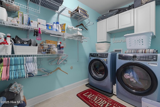 laundry room with washing machine and clothes dryer, baseboards, and cabinet space