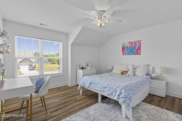 bedroom featuring ceiling fan, visible vents, vaulted ceiling, wood finished floors, and baseboards