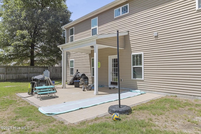 back of property featuring a yard, fence, and a patio area