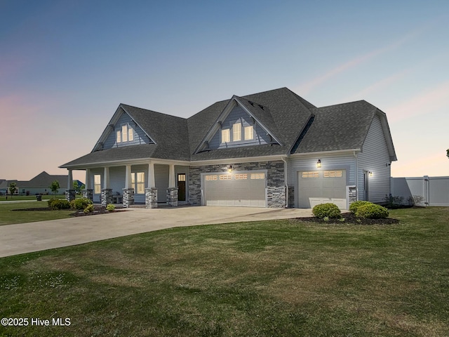 craftsman house featuring concrete driveway, covered porch, a garage, roof with shingles, and stone siding