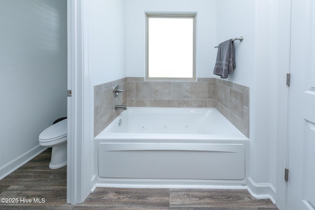 full bathroom with toilet, a tub with jets, and wood finished floors