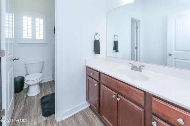 full bathroom with wood finished floors, vanity, baseboards, and toilet