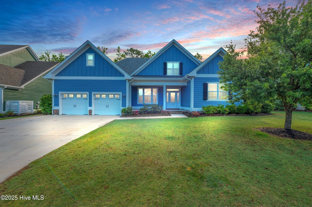 craftsman house with board and batten siding, a garage, driveway, and a lawn