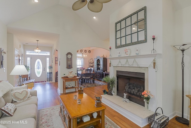 living room featuring ceiling fan, arched walkways, high vaulted ceiling, and wood finished floors