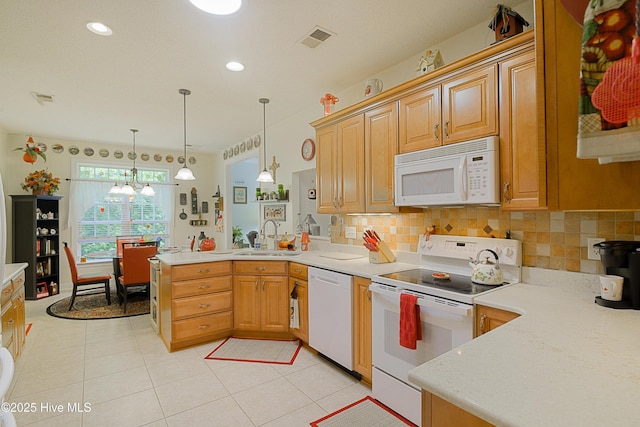 kitchen with a peninsula, a sink, visible vents, white appliances, and light countertops
