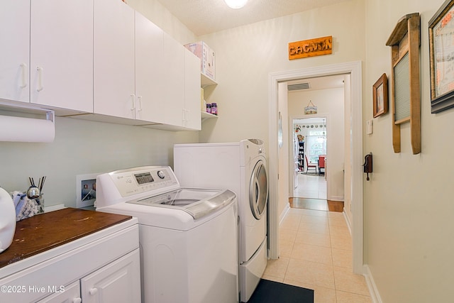 clothes washing area featuring baseboards, light tile patterned floors, visible vents, washing machine and clothes dryer, and cabinet space