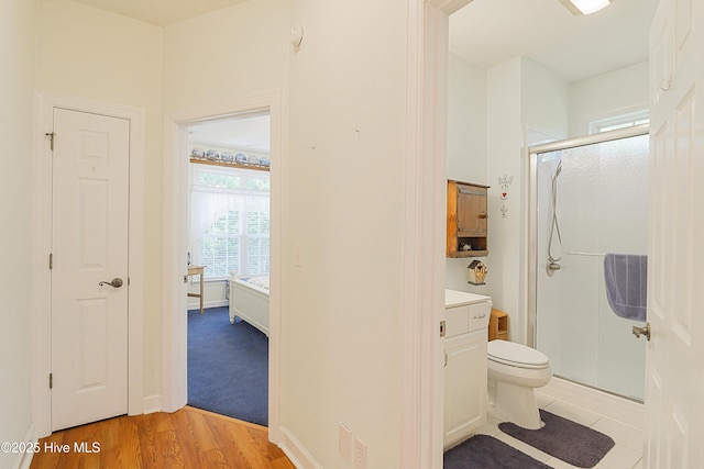 full bath featuring a stall shower, toilet, and wood finished floors