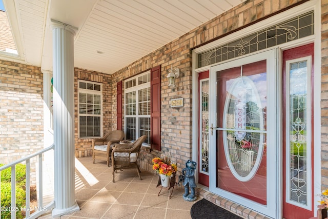 property entrance featuring a porch and brick siding