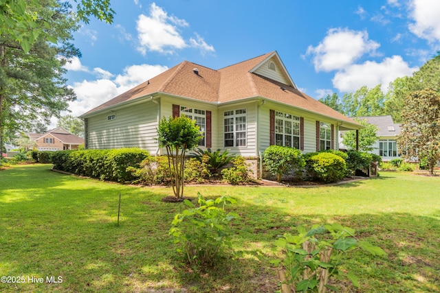 view of side of property with a lawn and a shingled roof