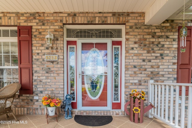 property entrance with a porch and brick siding