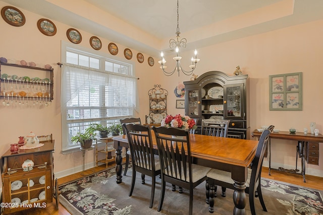 dining space with baseboards, a chandelier, and wood finished floors