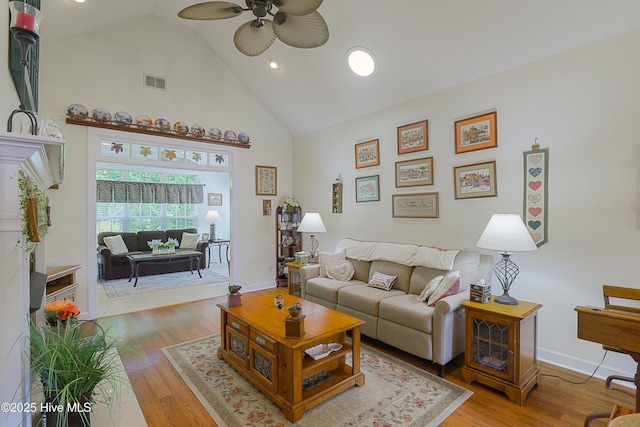 living area with ceiling fan, high vaulted ceiling, visible vents, and wood finished floors