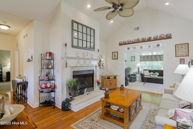 living room featuring a fireplace, ceiling fan, visible vents, and wood finished floors