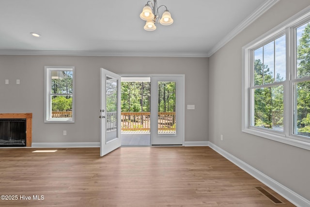doorway with plenty of natural light, baseboards, ornamental molding, a chandelier, and light wood-style floors