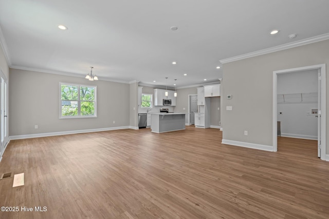 unfurnished living room featuring crown molding, recessed lighting, light wood-type flooring, baseboards, and a chandelier
