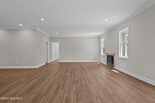unfurnished living room featuring crown molding, recessed lighting, light wood-type flooring, a fireplace, and baseboards