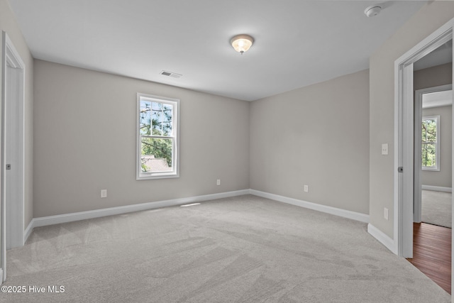 carpeted empty room featuring healthy amount of natural light, a smoke detector, and baseboards