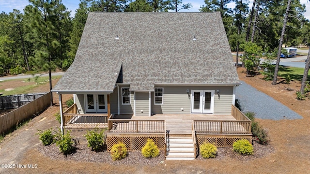 rear view of property featuring french doors, a wooden deck, fence, and a shingled roof