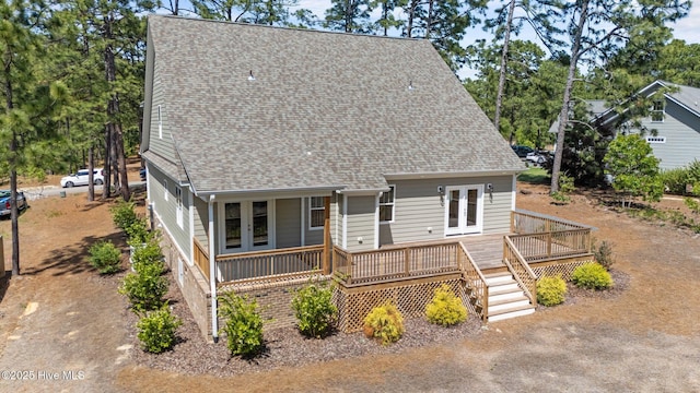 rear view of property with french doors, roof with shingles, and a deck