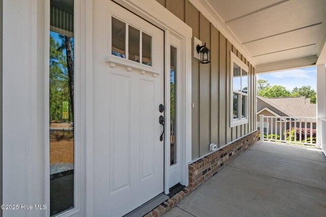 doorway to property featuring board and batten siding and covered porch
