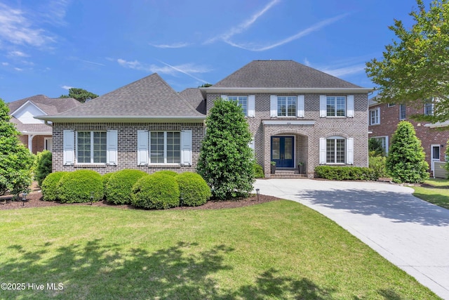 view of front of home with brick siding, a front lawn, and driveway