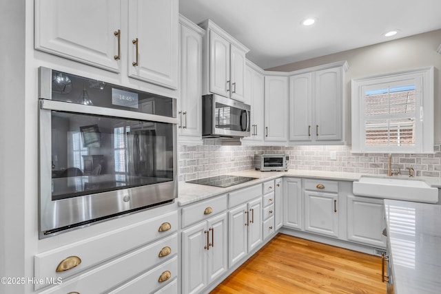 kitchen featuring white cabinetry, appliances with stainless steel finishes, a sink, and tasteful backsplash