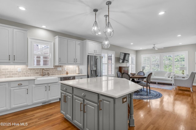 kitchen featuring gray cabinetry, white cabinets, stainless steel refrigerator with ice dispenser, and a sink