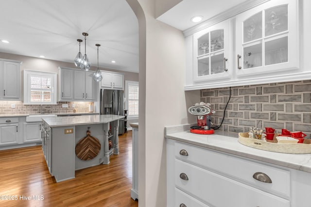 kitchen with stainless steel fridge, a sink, decorative backsplash, and white cabinetry