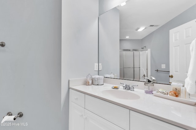 bathroom featuring a shower with shower door, vanity, and visible vents