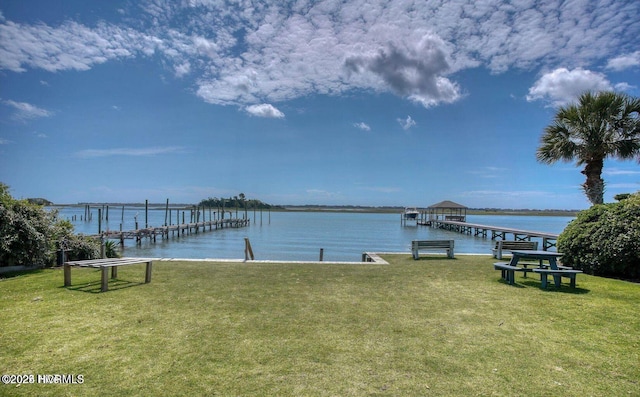 view of dock with a yard and a water view