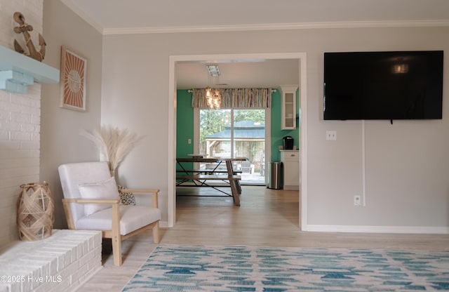 sitting room featuring light wood-type flooring, baseboards, ornamental molding, and a chandelier