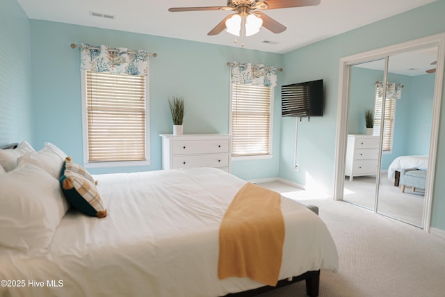 carpeted bedroom featuring a closet, multiple windows, a ceiling fan, and baseboards