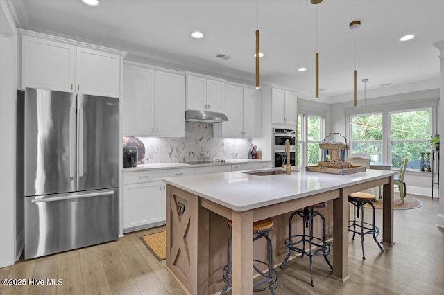 489 Broomsedge Ct SE, Bolivia, NC 28422 - kitchen with stainless steel appliances, a sink, under cabinet range hood, an island with sink, and white cabinetry