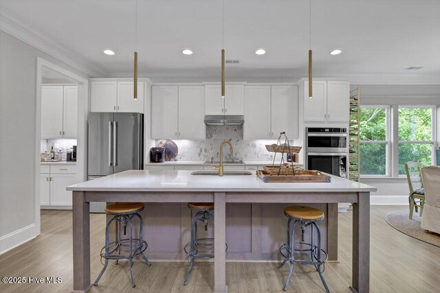 489 Broomsedge Ct SE, Bolivia, NC 28422 - kitchen with stainless steel appliances, crown molding, under cabinet range hood, decorative backsplash, and white cabinets