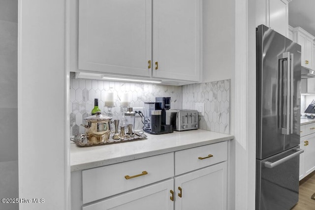 489 Broomsedge Ct SE, Bolivia, NC 28422 - kitchen with high end refrigerator, white cabinetry, tasteful backsplash, and wood finished floors