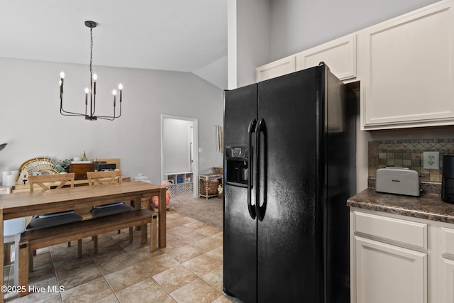 kitchen featuring black refrigerator with ice dispenser, lofted ceiling, dark countertops, tasteful backsplash, and a notable chandelier