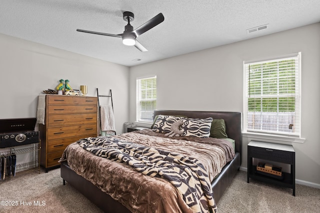 bedroom with carpet floors, a textured ceiling, ceiling fan, and visible vents