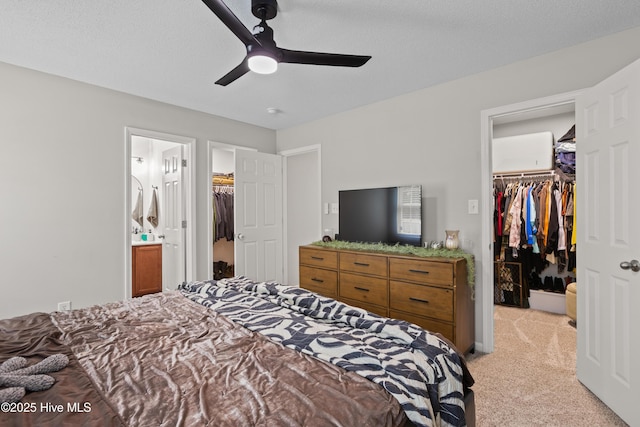 bedroom featuring light colored carpet, a walk in closet, ensuite bathroom, and a closet