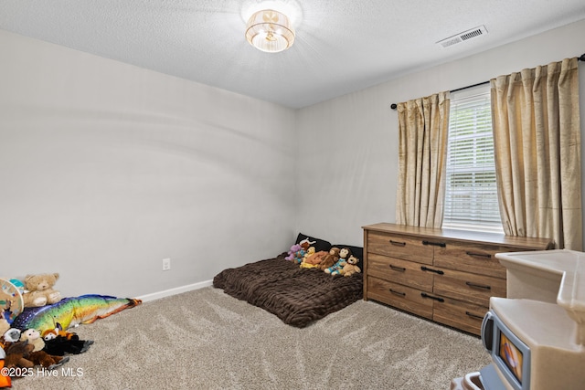 carpeted bedroom with a textured ceiling, baseboards, visible vents, and a wood stove
