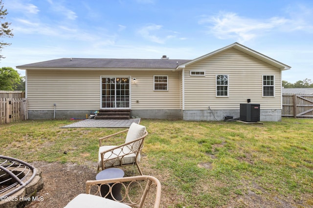 back of house with a fenced backyard, central AC, and a yard